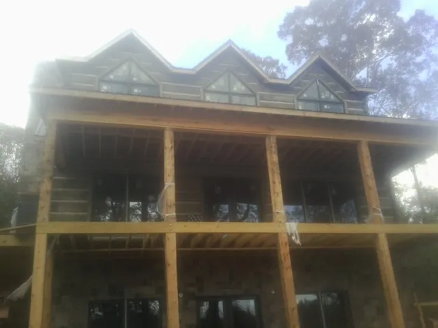 Dormers and porch framing on a large log home under construction — Roof Coating work by our crew in North Grafton