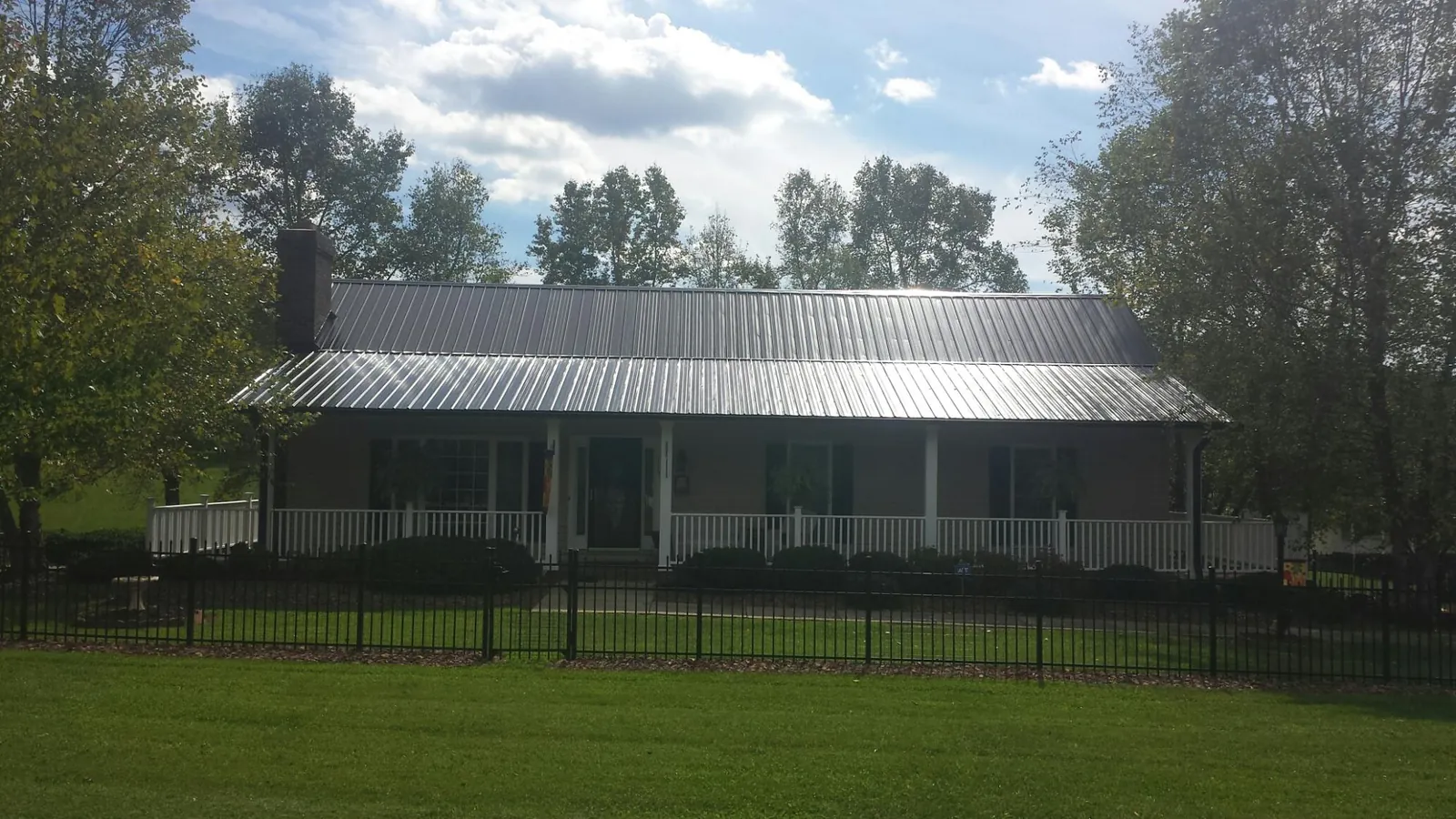 Gray metal roof on a brick ranch with a full width front porch — Gutter Guard Installation work by our crew in North Grafton