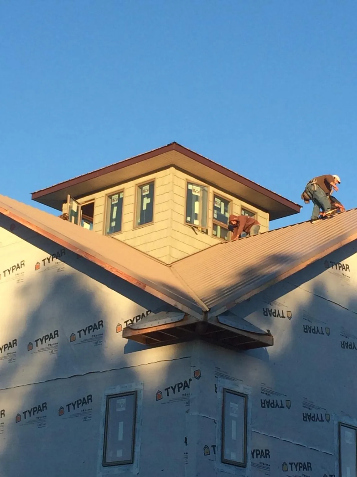 Roofers working around a rooftop cupola on a new metal roof at sunset — Roof Waterproofing in North Grafton by Roofing Brothers